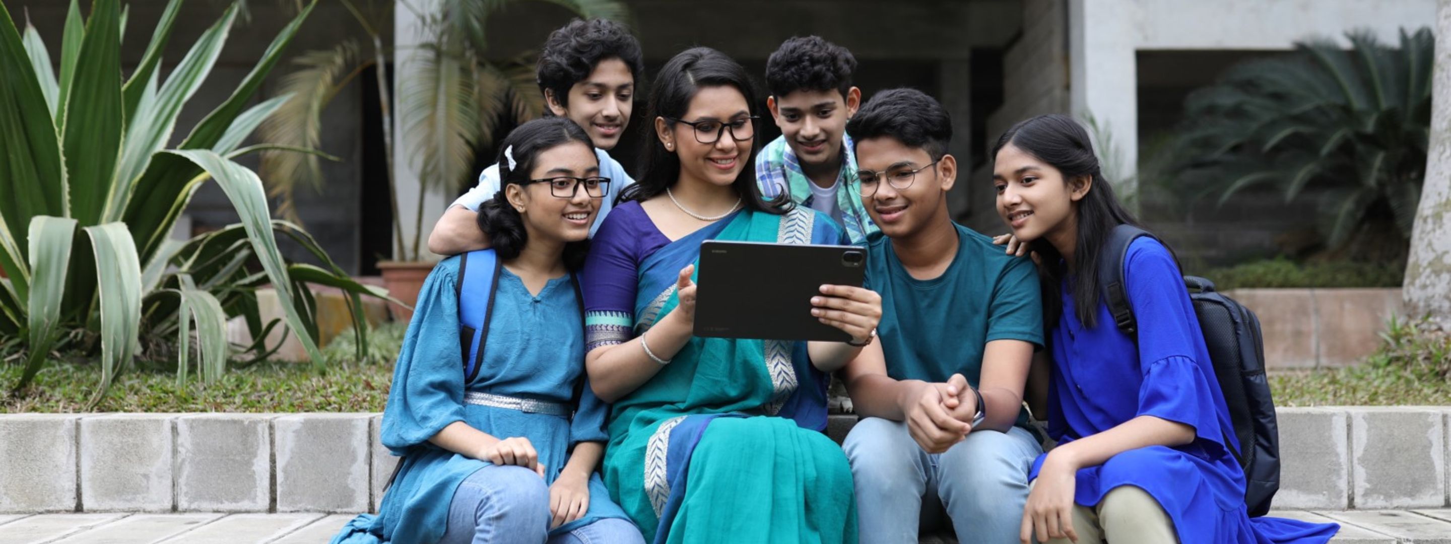 One women and six youths sitting with a tablet.